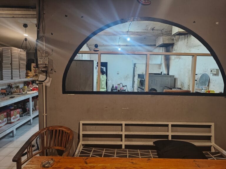 A wood-fired pizza at Angelo’s Pizza in Jimbaran, served in a cozy, rustic setting.